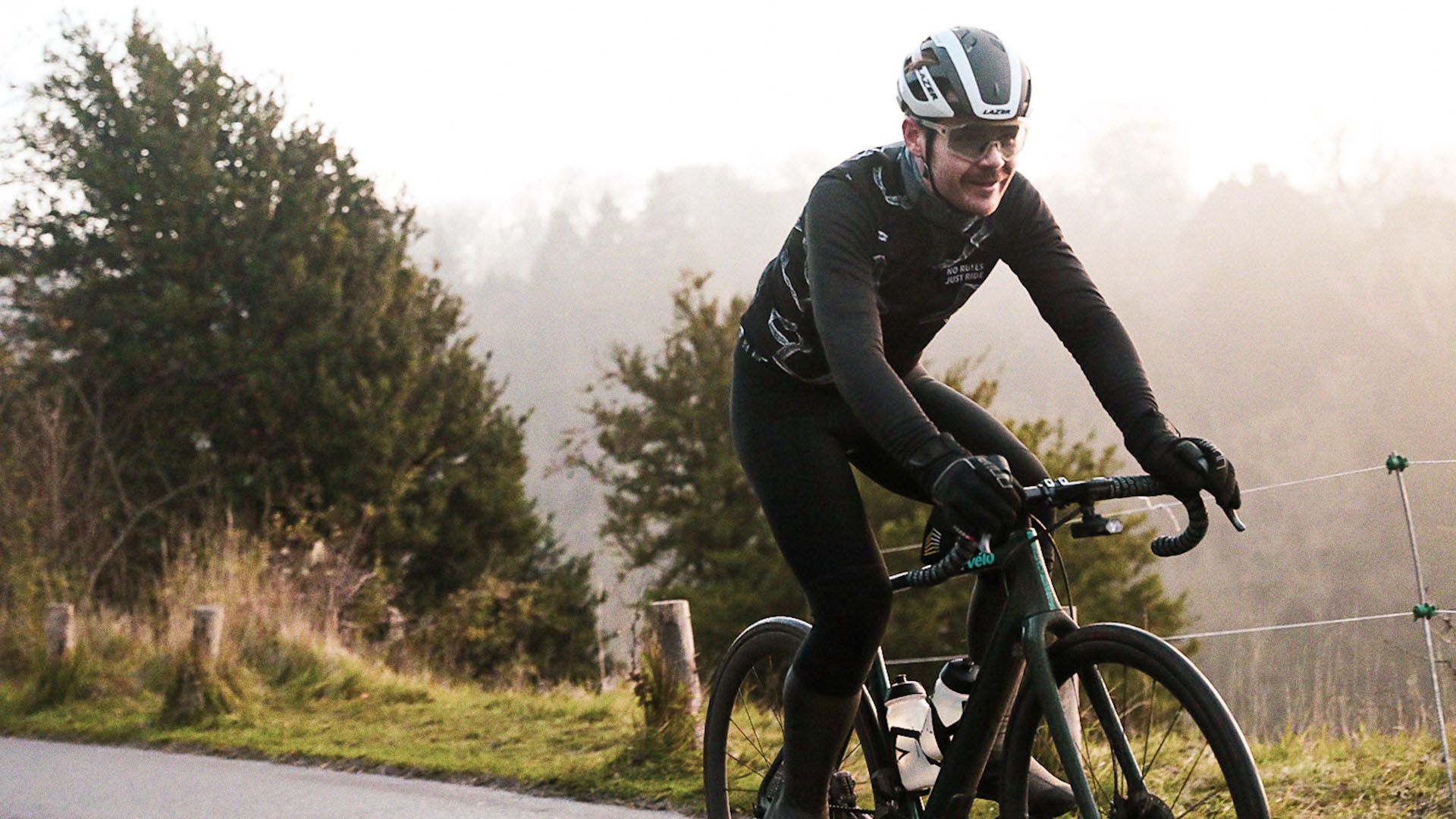 Two athletic cyclists in full gear, smiling and riding to camera.