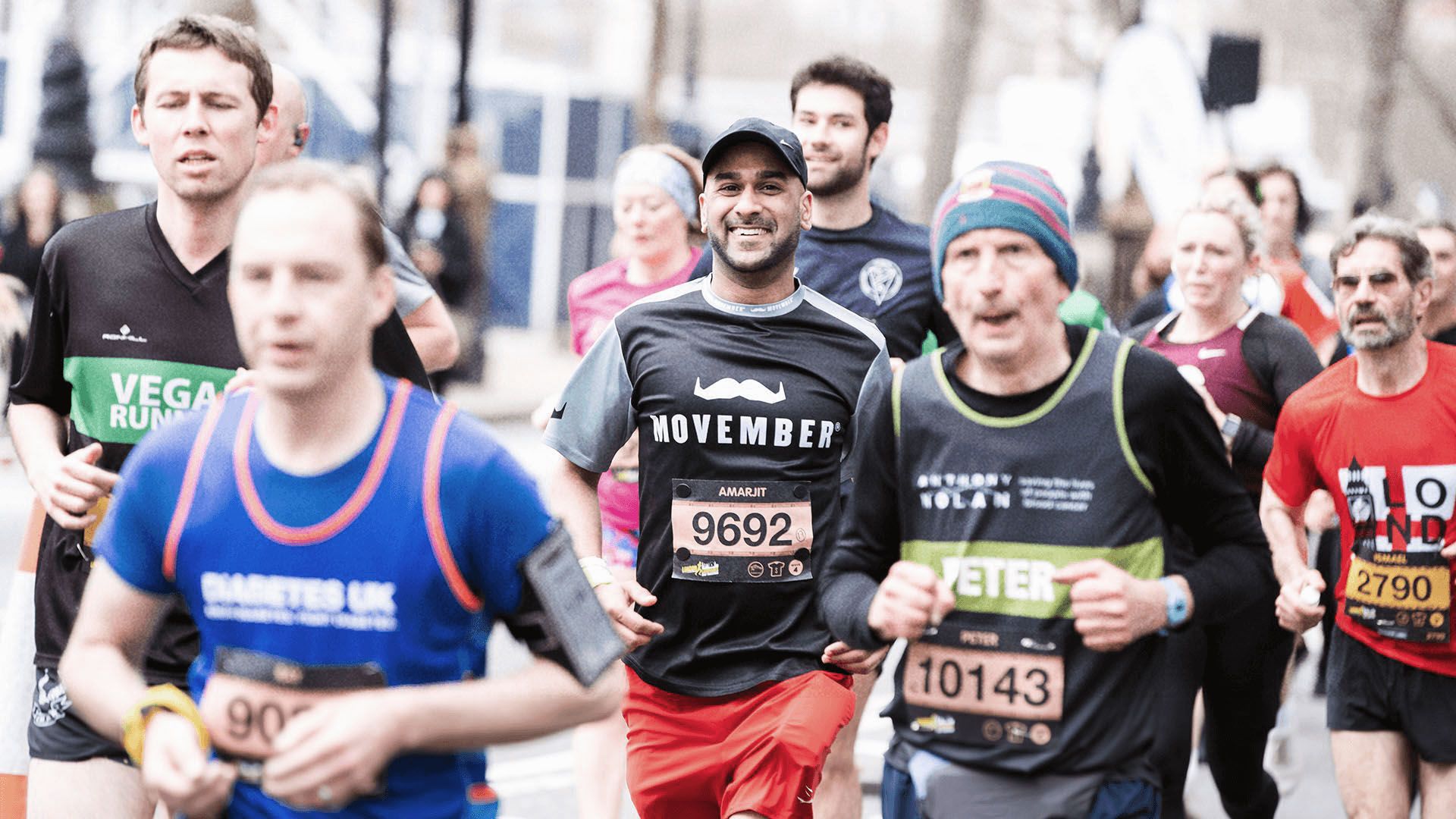 Smiling marathon runners in Movember-branded attire smiling to camera.