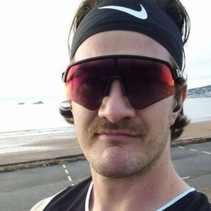 Photo of an athletic man looking to camera, wearing spectacular running sunglasses and an equally spectacular moustache.