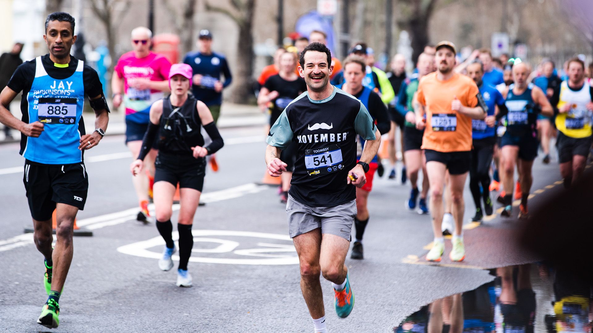 Smiling marathon runner in Movember-branded attire looking to camera.