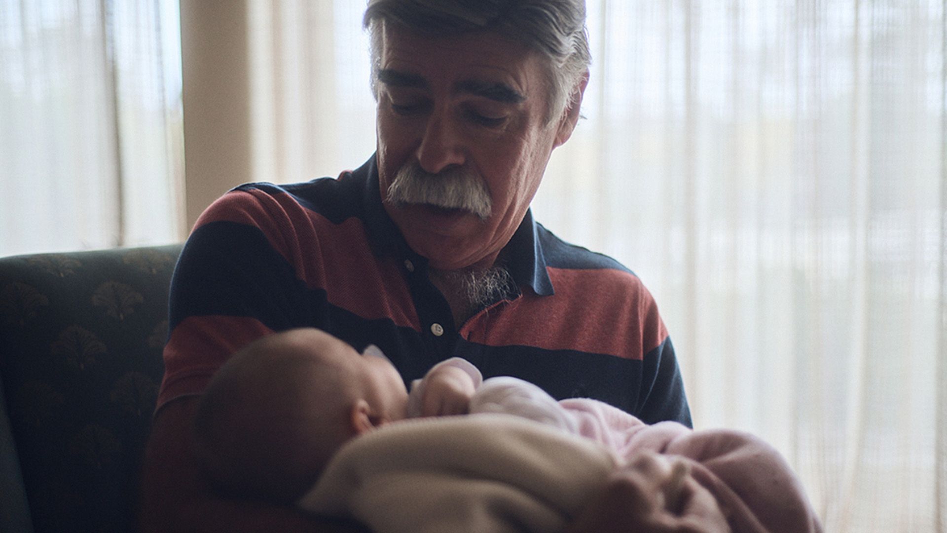 Photo of a grandfather lovingly cradling an infant.