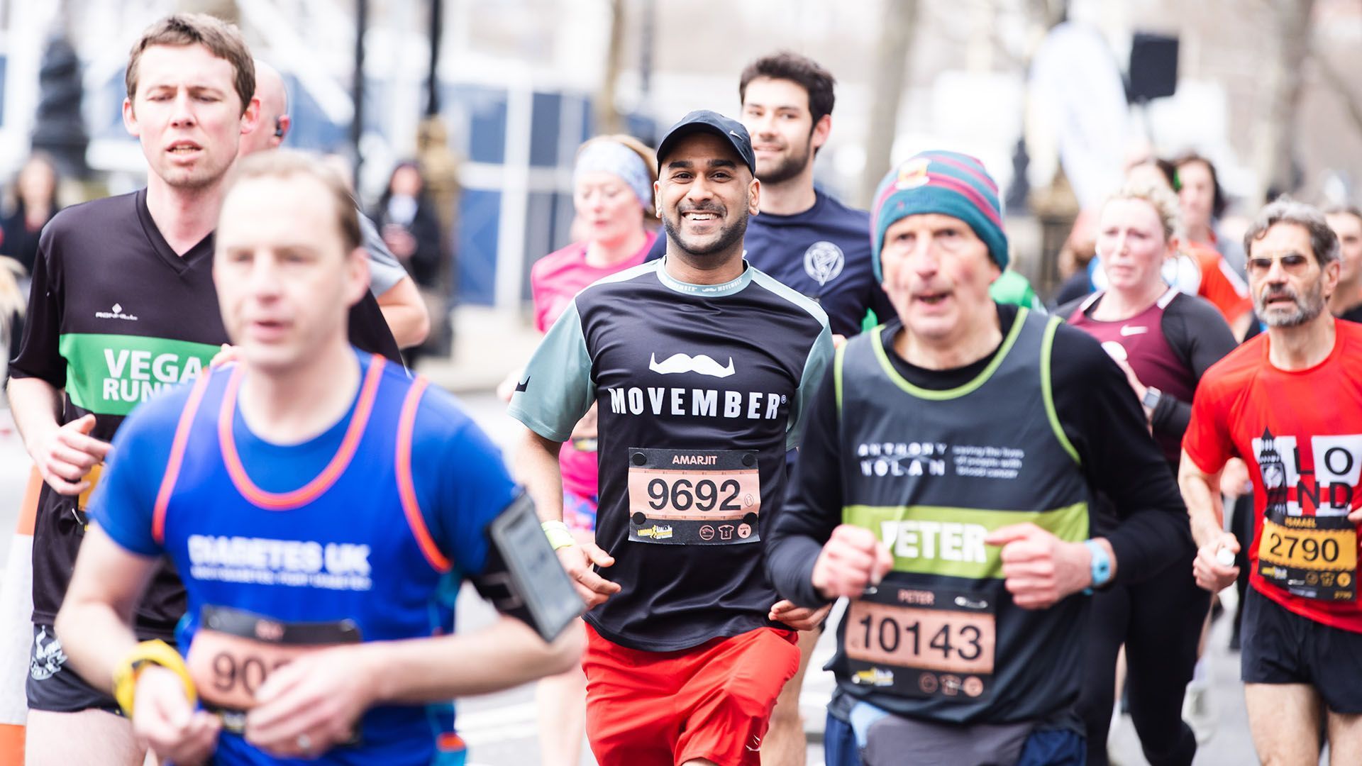 Smiling marathon runners in Movember-branded attire smiling to camera.